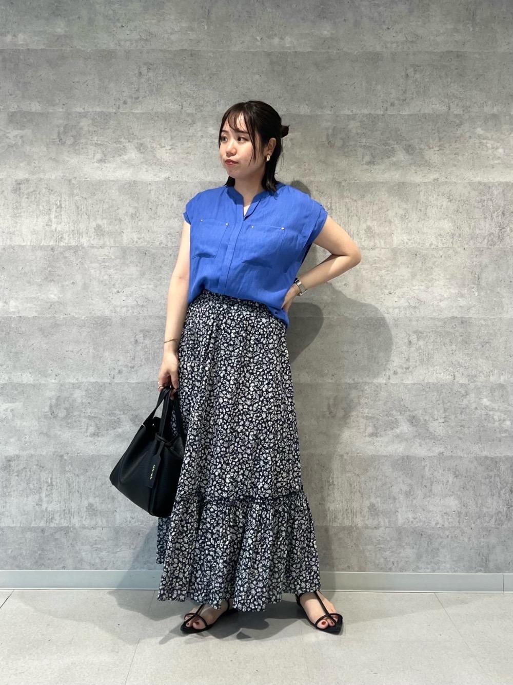 ブルー系のシャツ/ブラウス、ホワイト系のスカート、ブラック系のショルダーバッグを着用したレディースの夏コーディネートの1枚目の写真