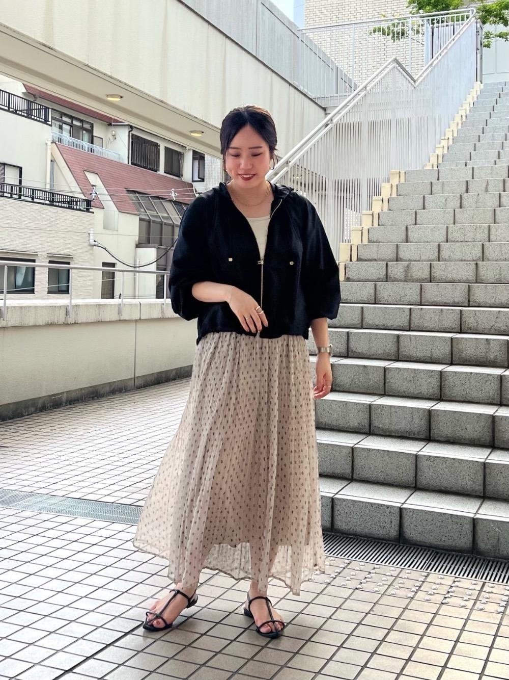 ベージュ系のタンクトップ、ホワイト系のスカート、ブラック系のブルゾンを着用したレディースの夏コーディネートの1枚目の写真