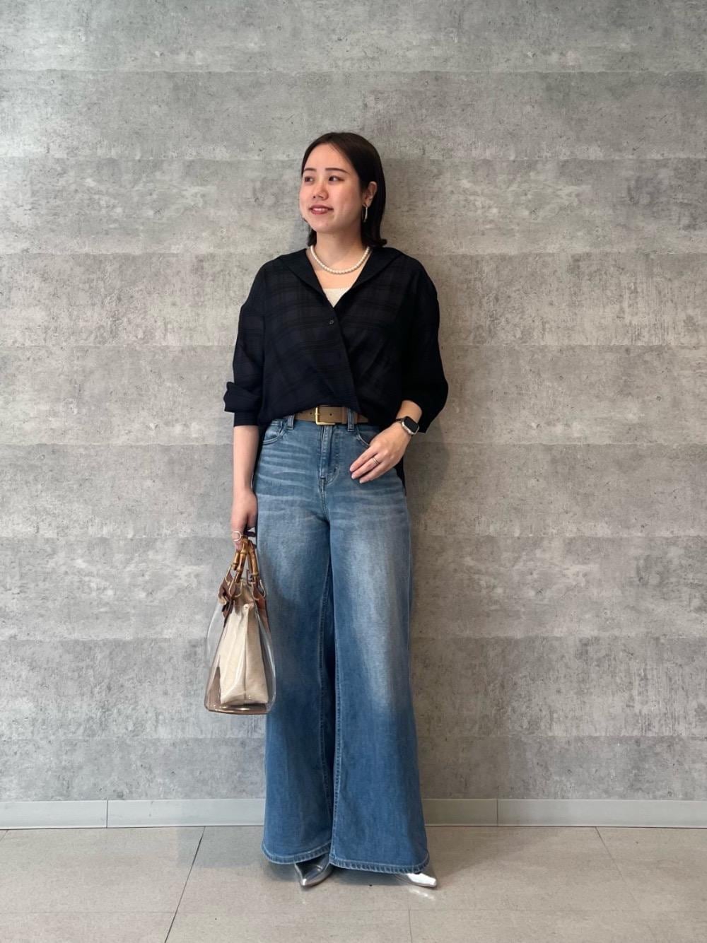 シルバー系のニット/セーター、ブラウン系のハンドバッグ、ブルー系のシャツ/ブラウスを着用したレディースの春コーディネートの1枚目の写真