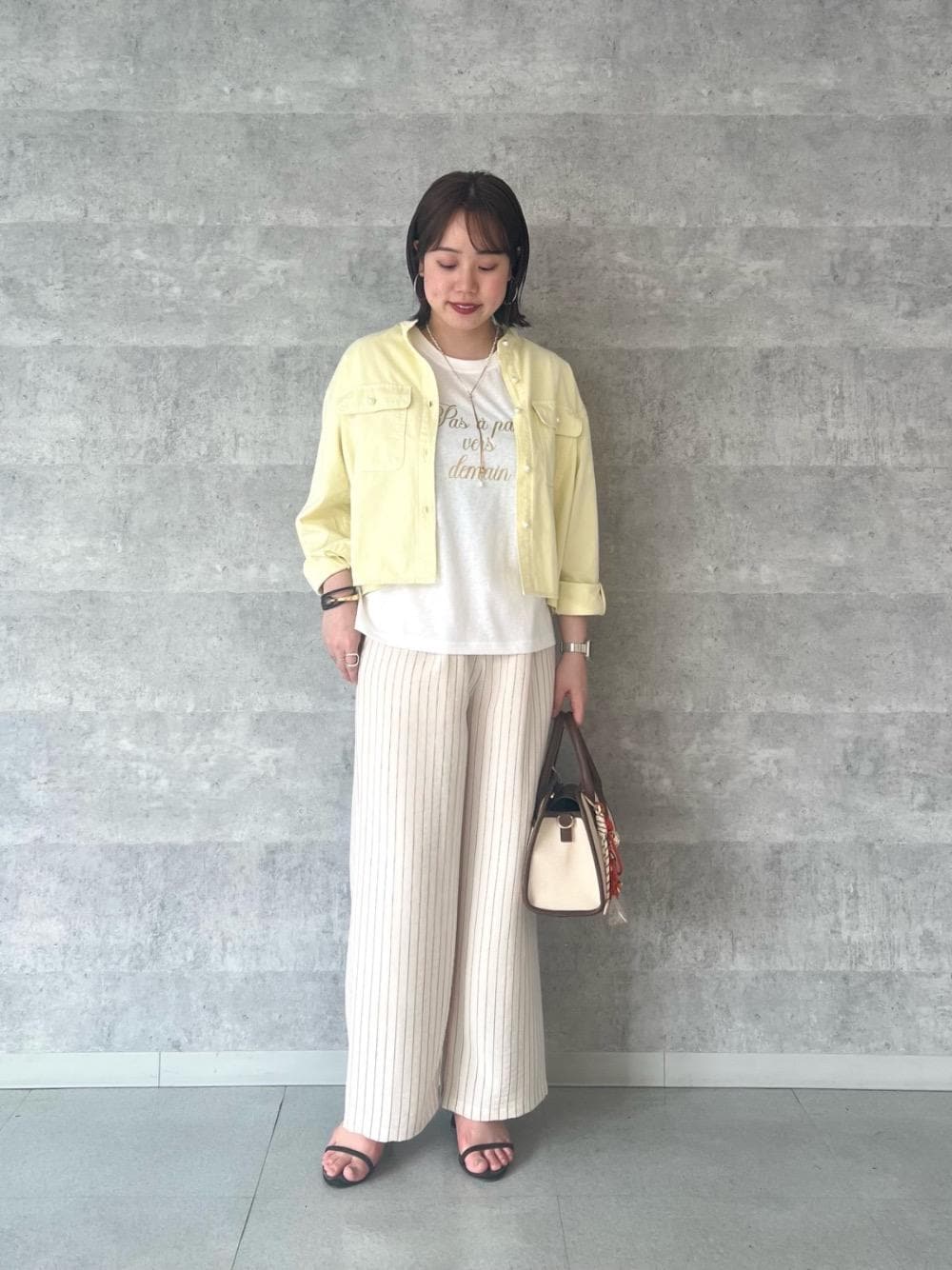 イエロー系のシャツ/ブラウス、オレンジ系のショルダーバッグ、ブラウン系のトートバッグを着用したレディースの春コーディネートの1枚目の写真