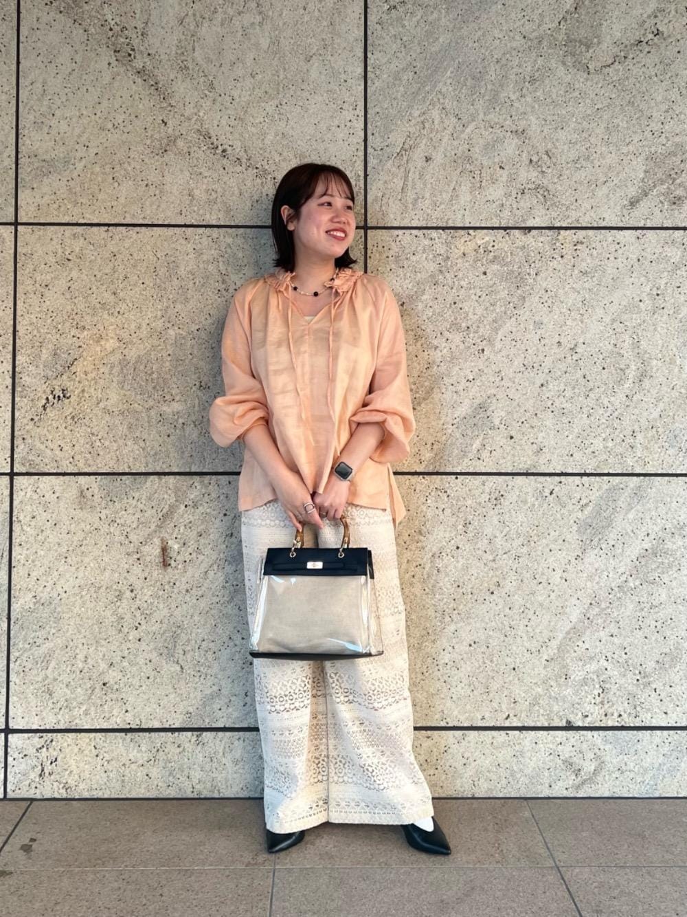 ブラック系のハンドバッグ、ブラック系のパンプス、ホワイト系のその他パンツを着用したレディースの春コーディネートの1枚目の写真