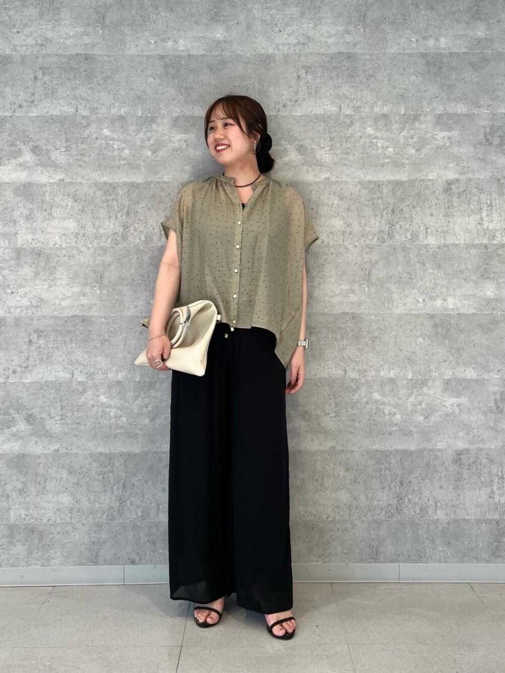 ブラック系のニット/セーター、ブラック系のその他パンツ、ベージュ系のシャツ/ブラウスを着用したレディースの春コーディネートの1枚目の写真