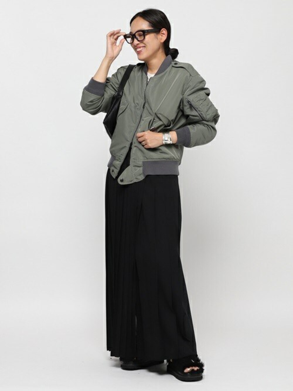 グリーン系のミリタリージャケット、ブラック系のスカート、シルバー系のブレスレットを着用したレディースの秋コーディネートの1枚目の写真