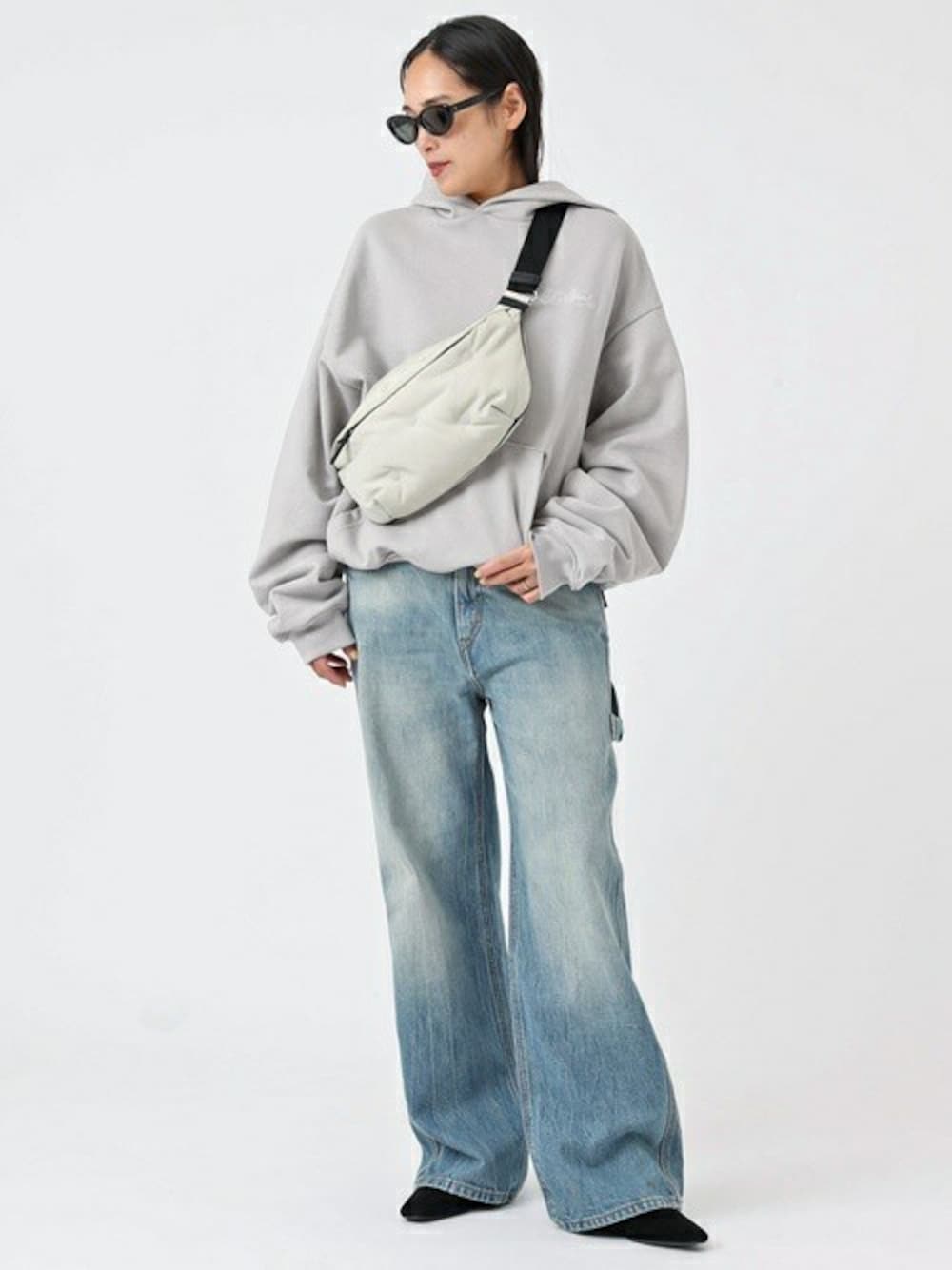 グレー系のパーカー、ブルー系のデニムパンツを着用したレディースの冬コーディネートの1枚目の写真