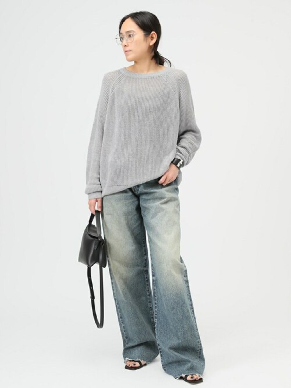 グレー系のニット/セーター、ブラック系のショルダーバッグ、ブラック系のブレスレットを着用したレディースの冬コーディネートの1枚目の写真