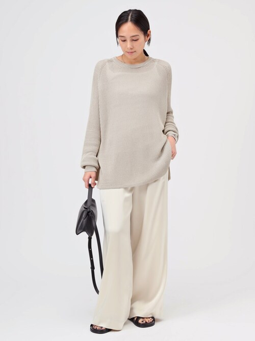 ベージュ系のニット/セーター、ホワイト系のスラックス、ブラック系のショルダーバッグを着用したレディースの冬コーディネートの1枚目の写真