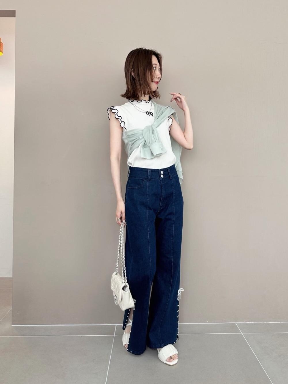 ブルー系のデニムパンツ、ホワイト系のサンダル、ホワイト系のTシャツ/カットソーを着用したレディースの春コーディネートの1枚目の写真