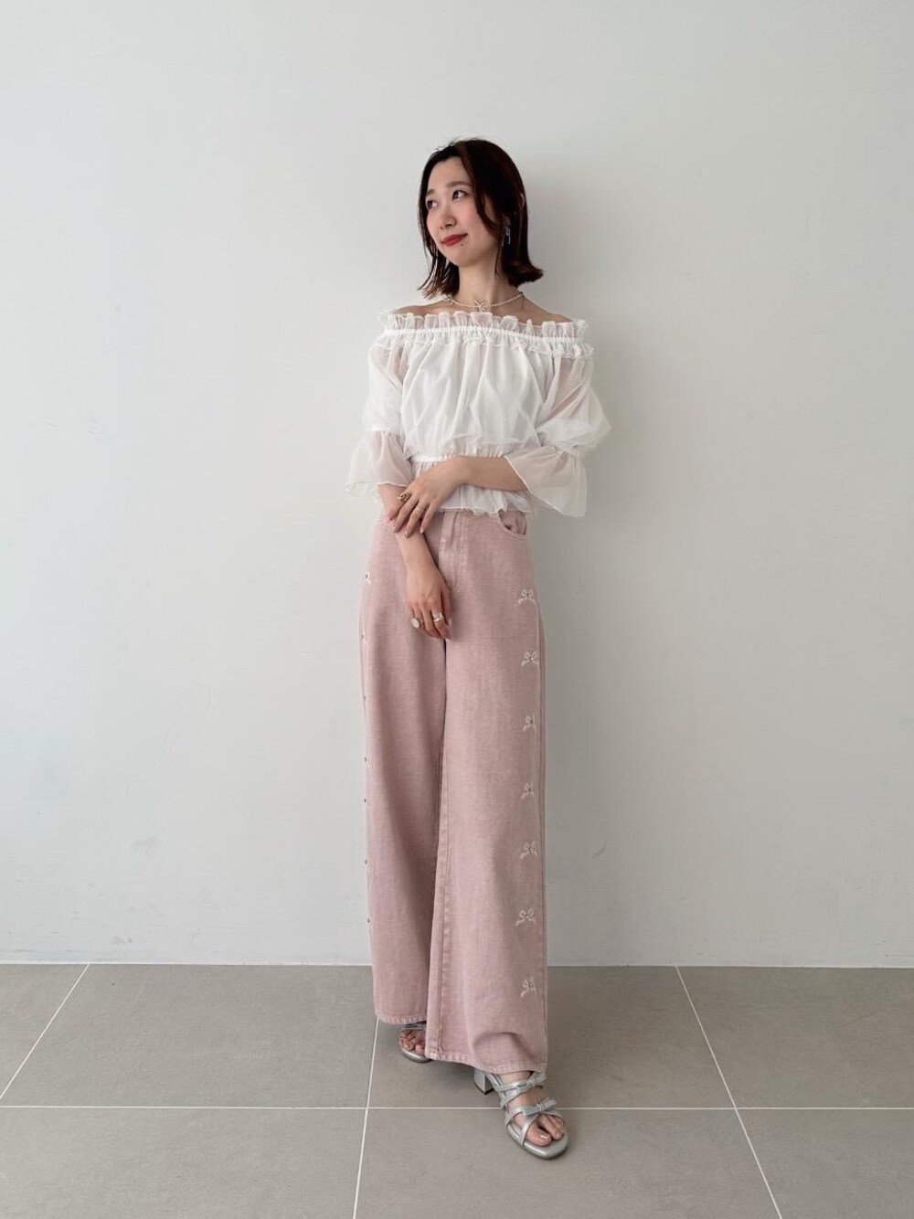 ピンク系のデニムパンツ、シルバー系のサンダル、その他のネックレスを着用したレディースの春コーディネートの1枚目の写真