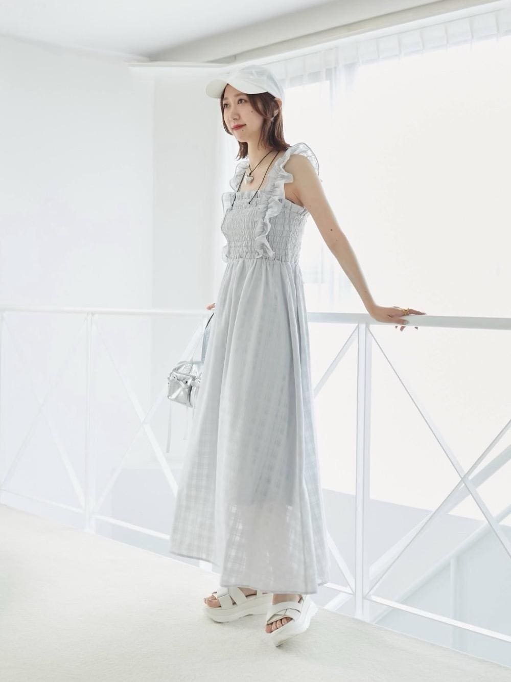 ホワイト系のサンダル、ブルー系のワンピース、ホワイト系のキャップを着用したレディースの春コーディネートの1枚目の写真