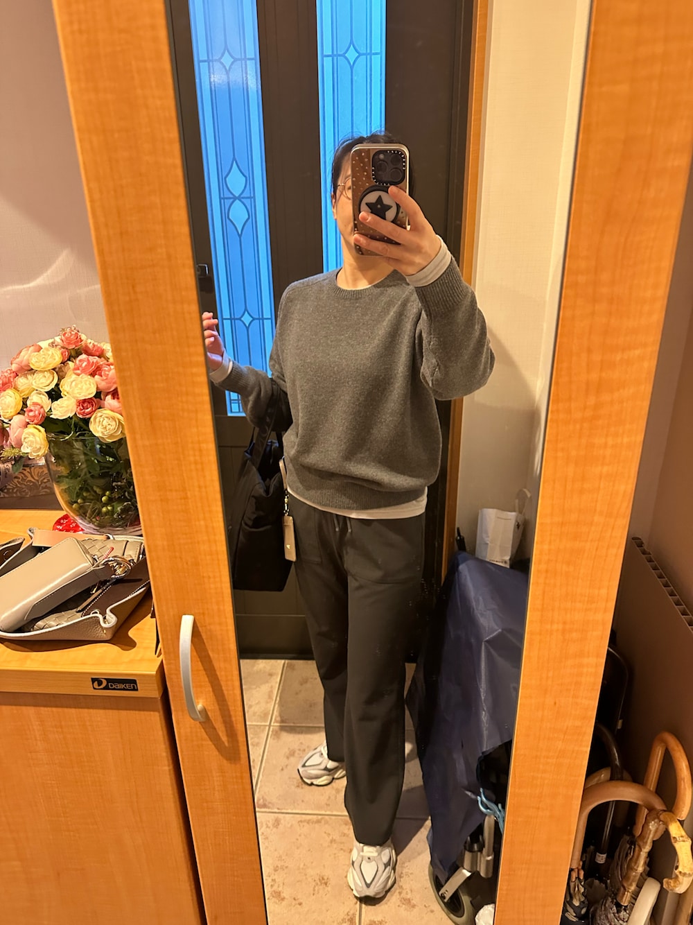 グレー系のニット/セーター、ブラック系のトートバッグ、グレー系のスラックスを着用したレディースの冬コーディネートの1枚目の写真