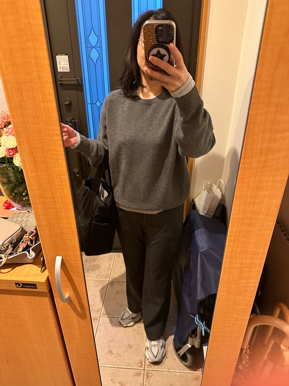 グレー系のスラックス、ブラック系のトートバッグ、グレー系のニット/セーターを着用したレディースの冬コーディネートの1枚目の写真