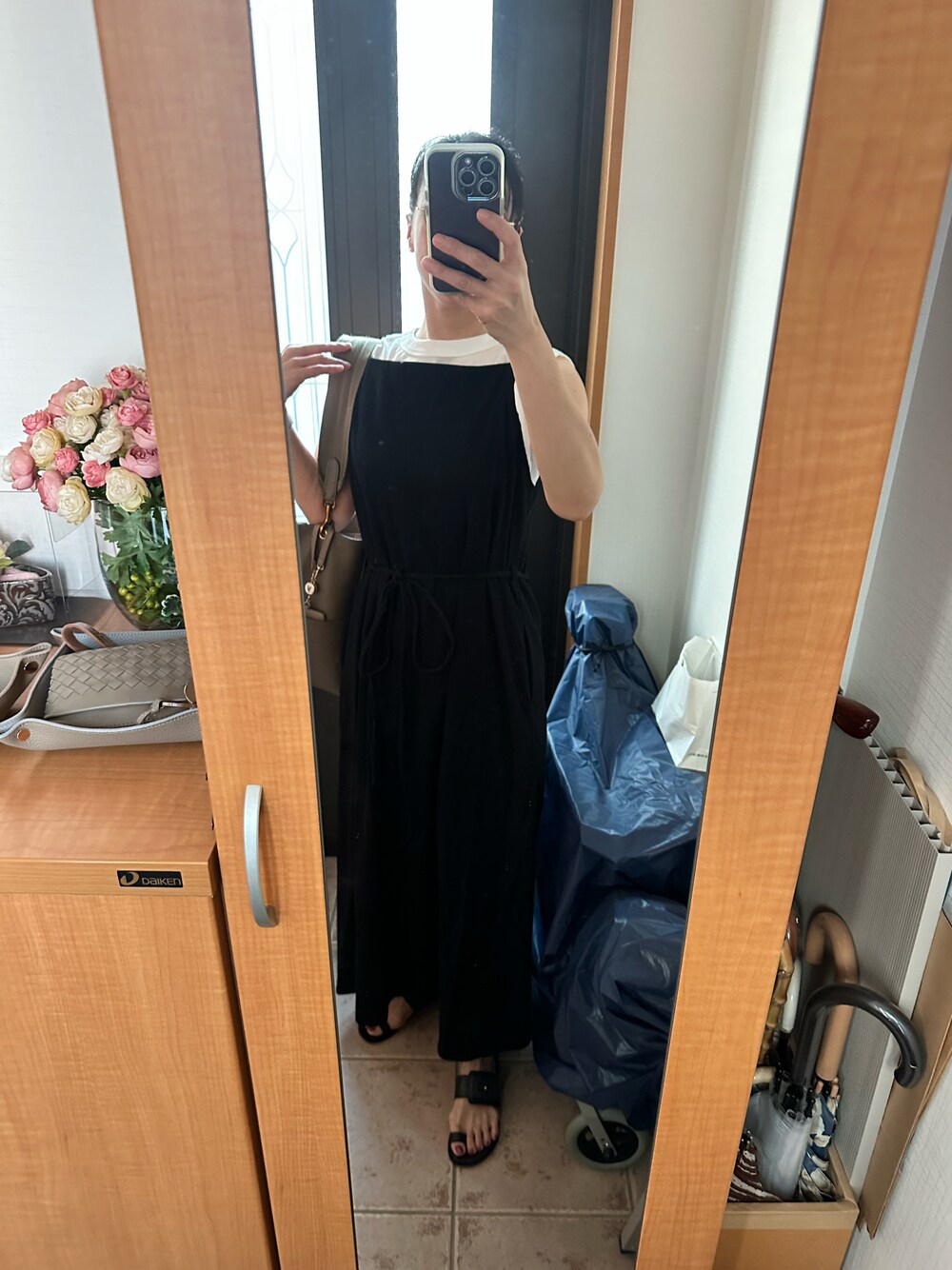 ブラック系のワンピース、ブラック系のサンダル、ホワイト系のTシャツ/カットソーを着用したレディースの夏コーディネートの1枚目の写真