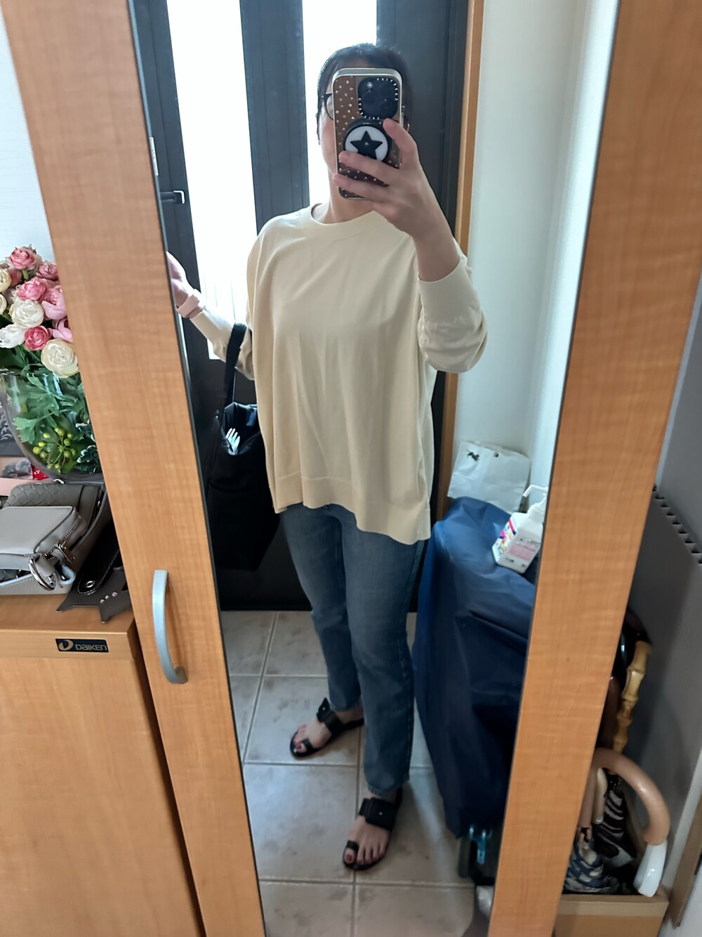 ベージュ系のニット/セーター、ブルー系のデニムパンツ、ブラック系のサンダルを着用したレディースの春コーディネートの1枚目の写真