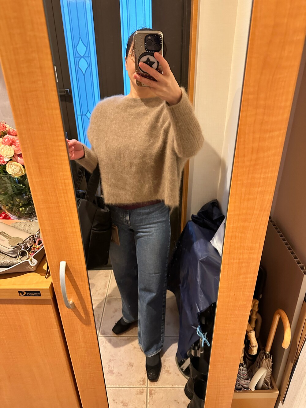 ブラウン系のニット/セーター、ブラック系のトートバッグ、ブルー系のデニムパンツを着用したレディースの冬コーディネートの1枚目の写真