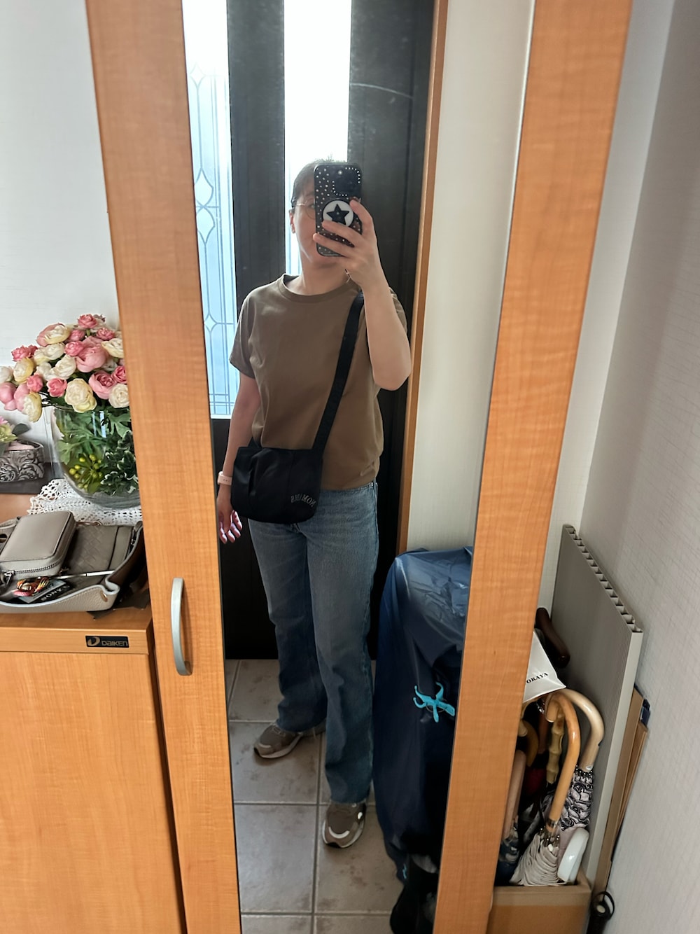 ブラウン系のTシャツ/カットソー、ブルー系のデニムパンツ、ベージュ系のスニーカーを着用したレディースの秋コーディネートの1枚目の写真