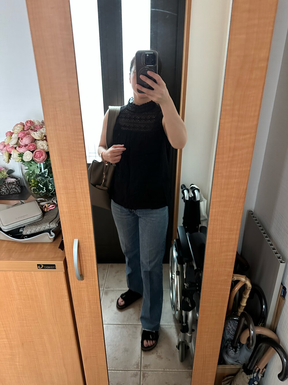 ブラック系のサンダル、ブラック系のシャツ/ブラウス、ブルー系のデニムパンツを着用したレディースの夏コーディネートの1枚目の写真