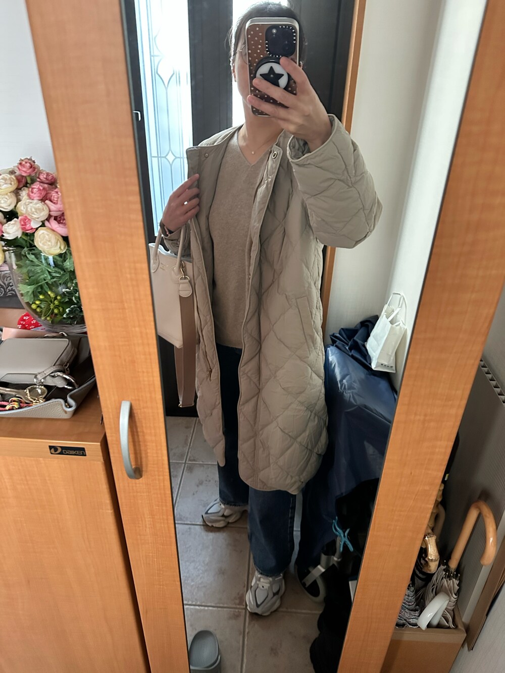 ベージュ系のダウンジャケット/コート、ベージュ系のニット/セーター、グレー系のスニーカーを着用したレディースの冬コーディネートの1枚目の写真