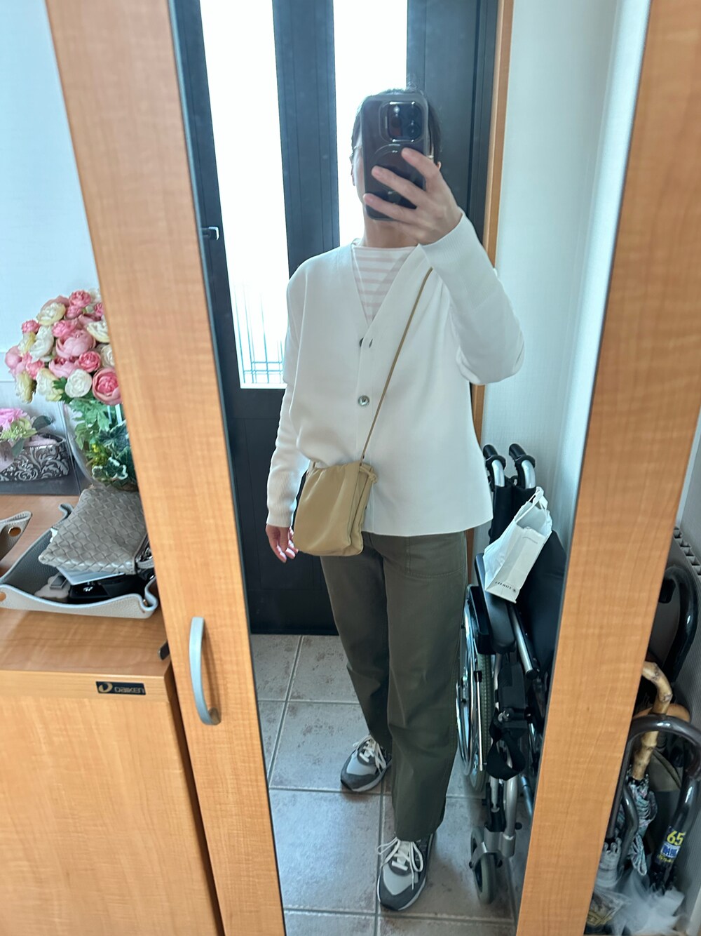 ホワイト系のカーディガン/ボレロ、ピンク系のTシャツ/カットソー、ベージュ系のショルダーバッグを着用したレディースの春コーディネートの1枚目の写真