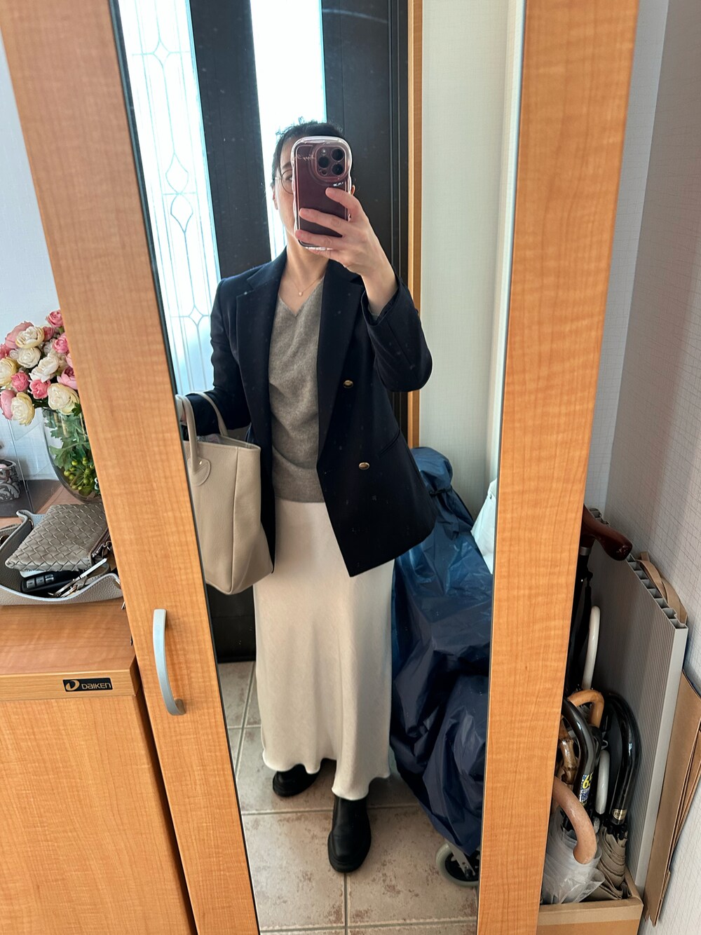 ブルー系のテーラードジャケット、ベージュ系のトートバッグ、ホワイト系のスカートを着用したレディースの秋コーディネートの1枚目の写真