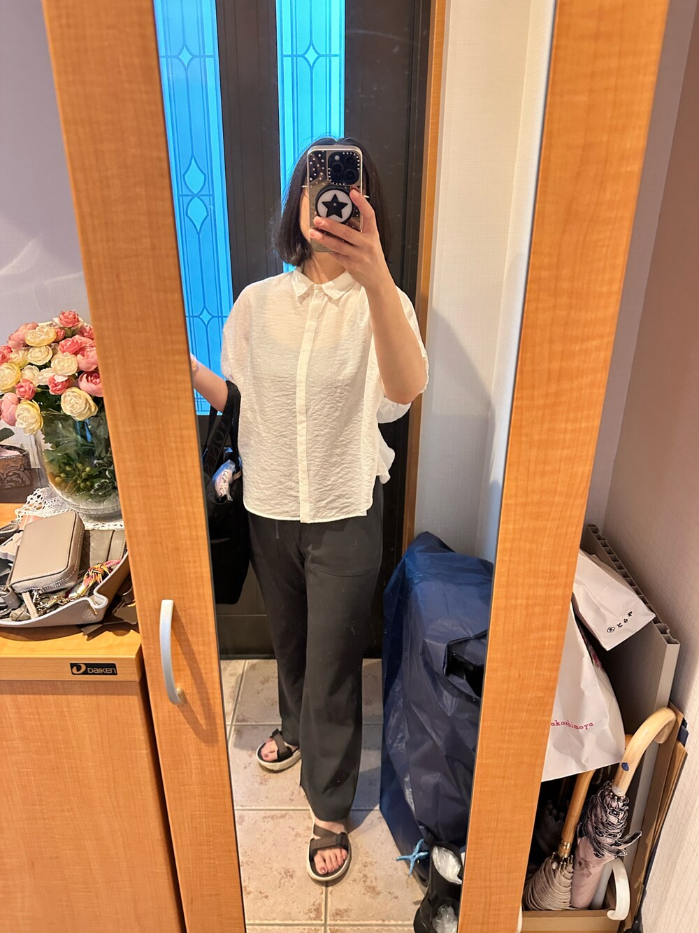 ホワイト系のシャツ/ブラウス、グレー系のスラックス、ブラウン系のサンダルを着用したレディースの夏コーディネートの1枚目の写真