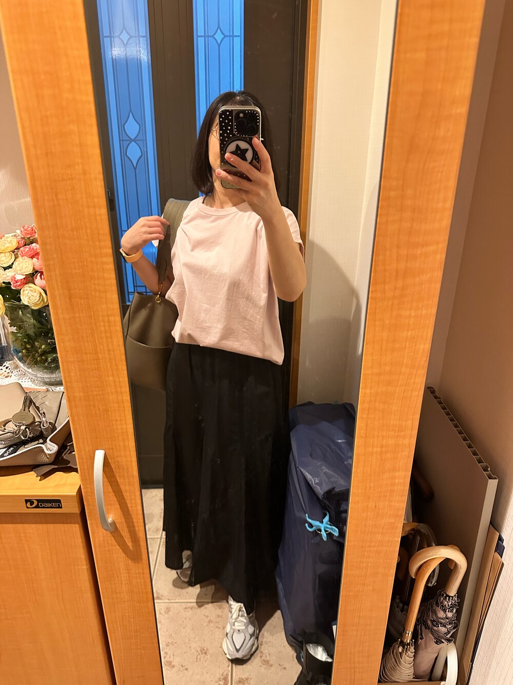 ピンク系のTシャツ/カットソー、ブラック系のスカート、グレー系のスニーカーを着用したレディースの秋コーディネートの1枚目の写真