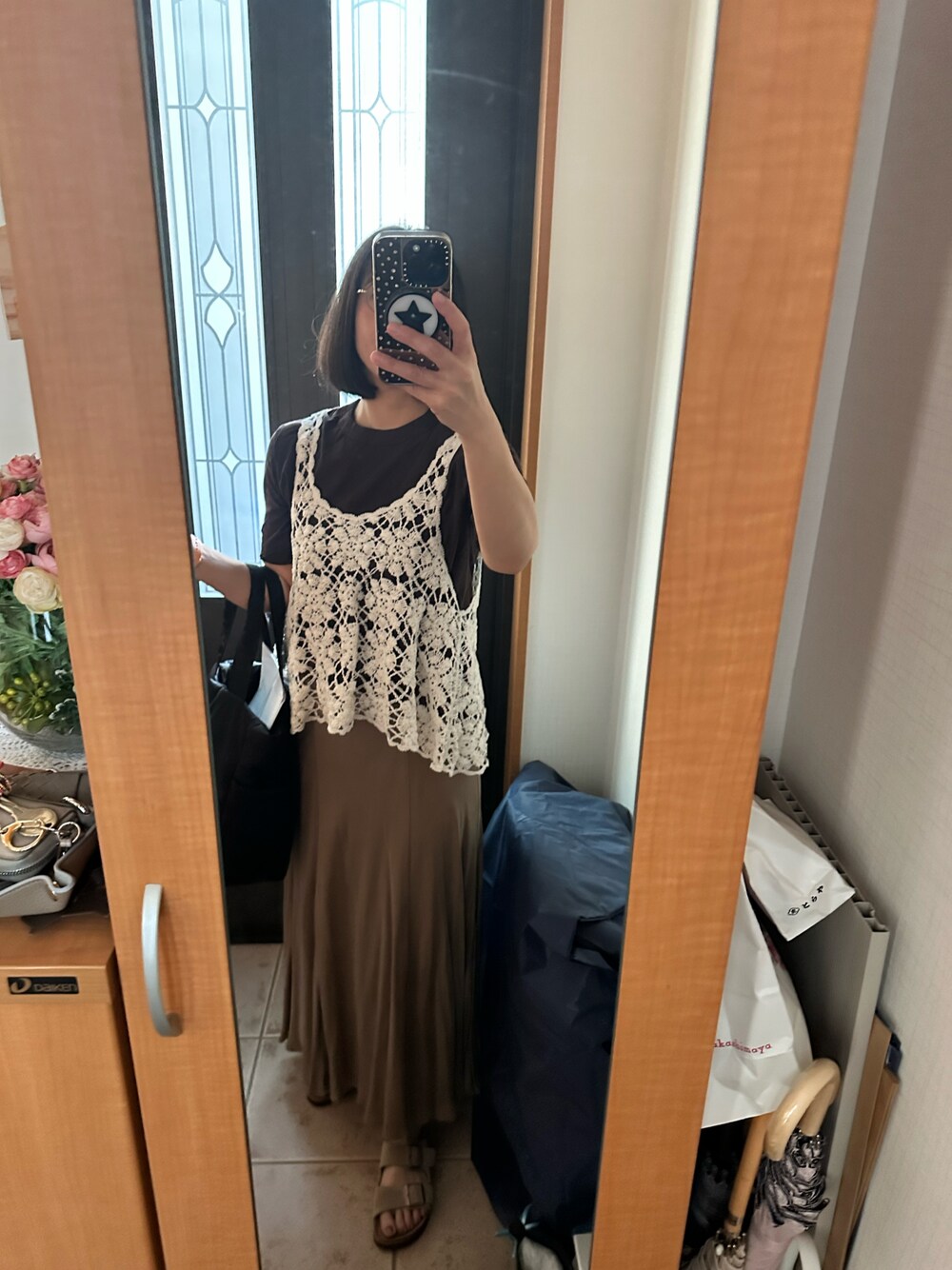 ベージュ系のスカート、ホワイト系のニット/セーター、ブラウン系のTシャツ/カットソーを着用したレディースの夏コーディネートの1枚目の写真