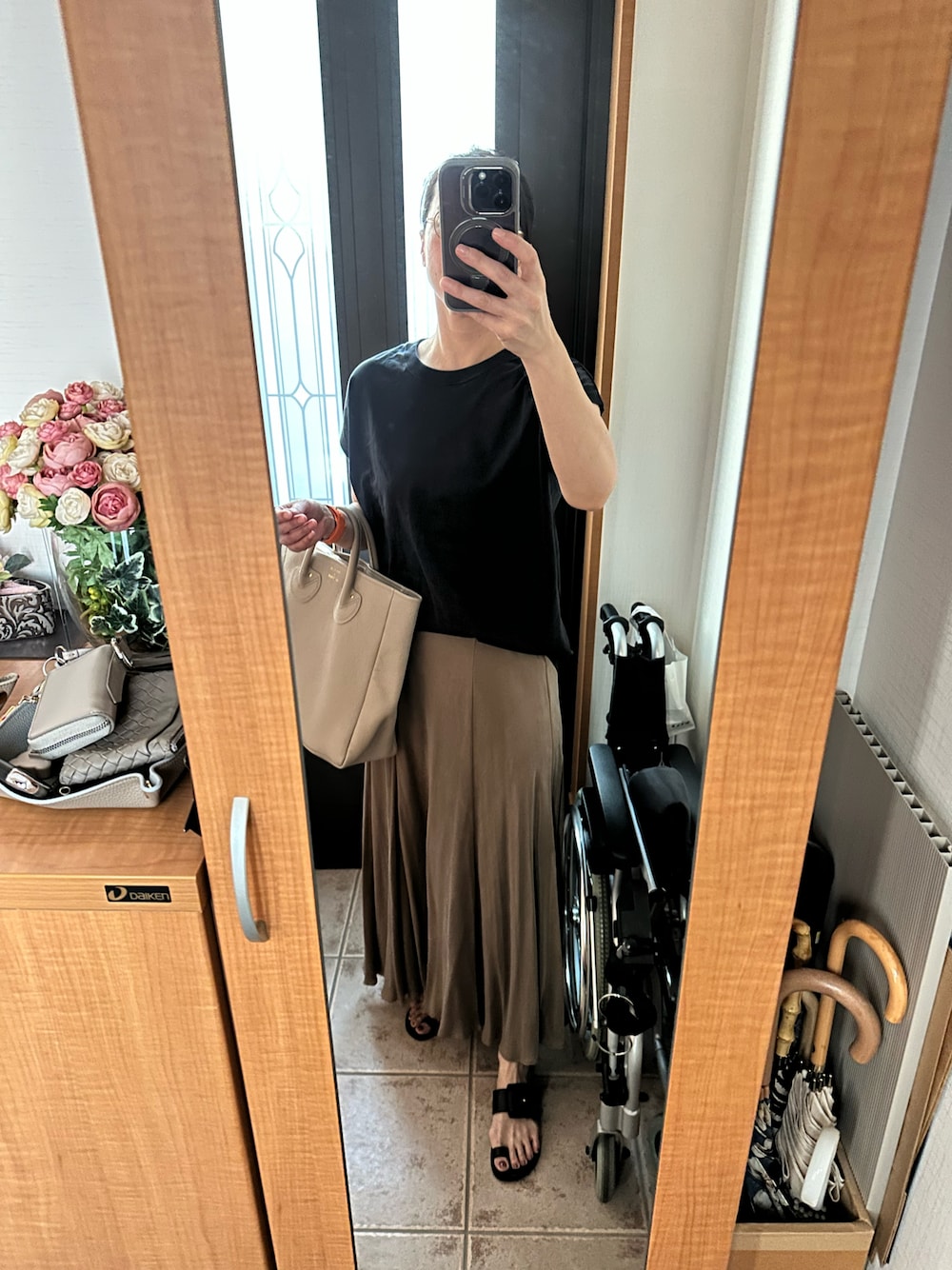 ブラック系のTシャツ/カットソー、ベージュ系のスカート、ベージュ系のトートバッグを着用したレディースの夏コーディネートの1枚目の写真