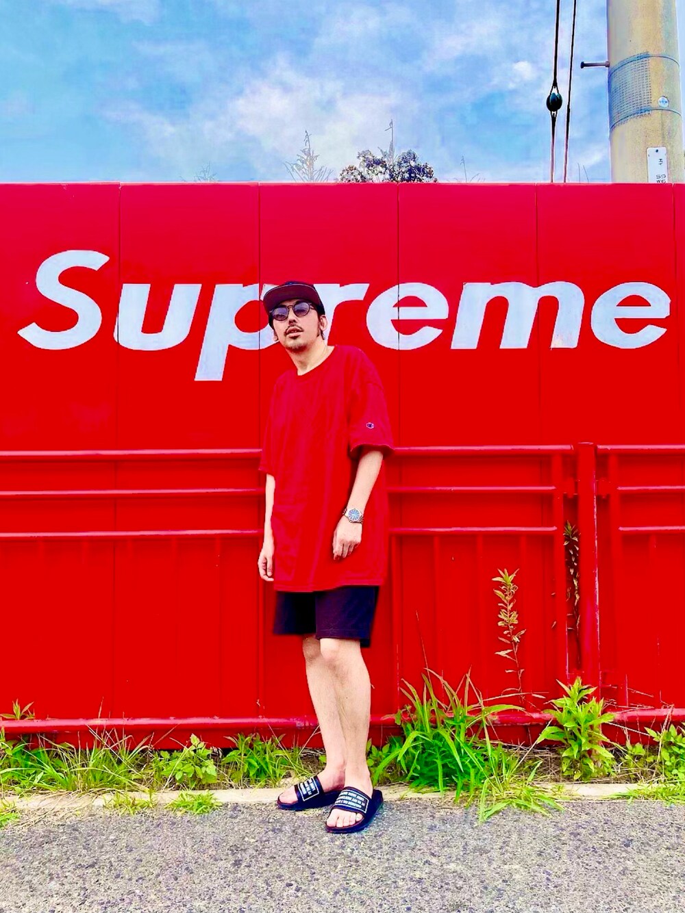 レッド系のTシャツ/カットソー、ブラック系のサンダル、ブラック系のキャップを着用したメンズの春コーディネートの1枚目の写真