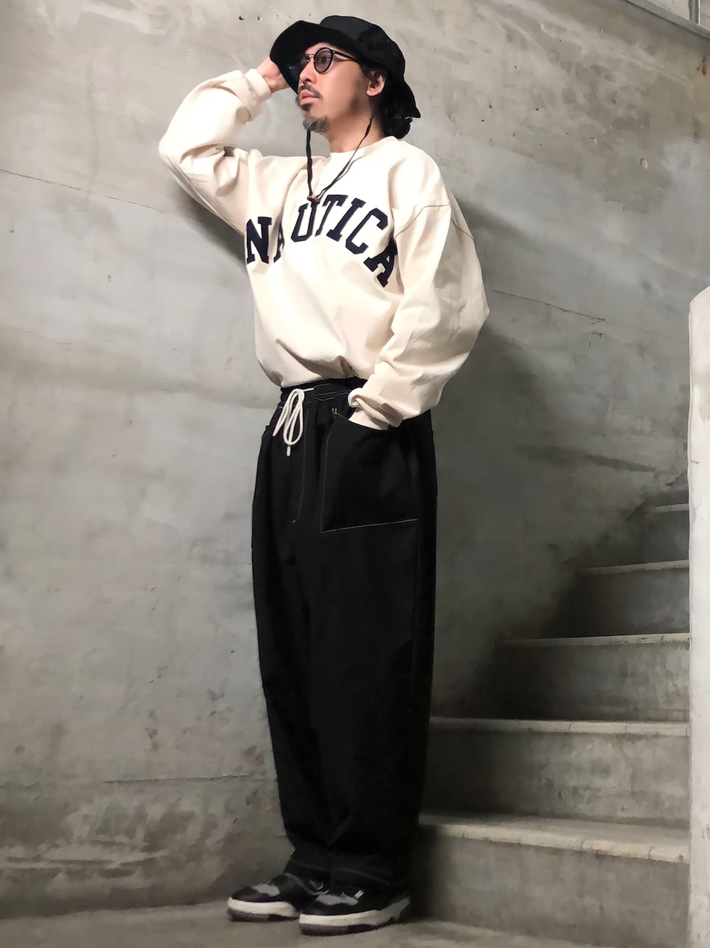 ベージュ系のTシャツ/カットソー、ブラック系のスニーカー、ブラック系のハットを着用したメンズの冬コーディネートの1枚目の写真