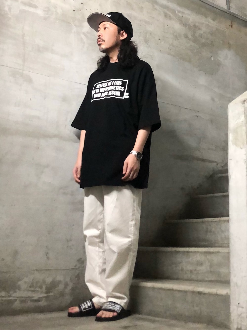 ブラック系のTシャツ/カットソー、ブラック系のサンダル、ブラック系のキャップを着用したメンズの夏コーディネートの1枚目の写真