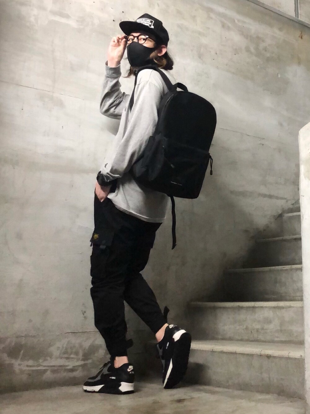 ブラック系のバックパック/リュック、ブラック系のスニーカー、ブラック系のキャップを着用したメンズの春コーディネートの1枚目の写真