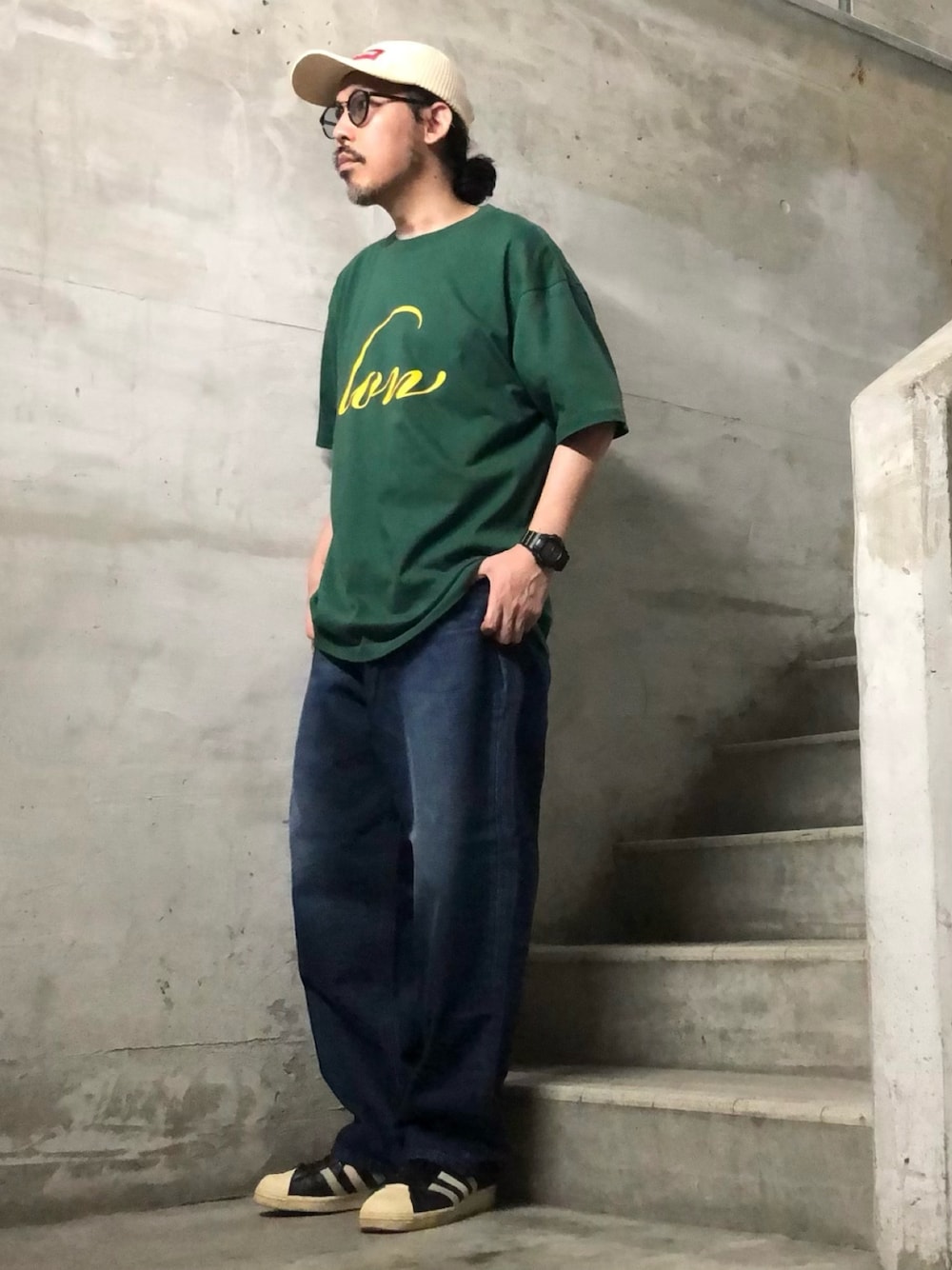 グリーン系のTシャツ/カットソー、ブルー系のデニムパンツ、ブラック系のスニーカーを着用したメンズの夏コーディネートの1枚目の写真