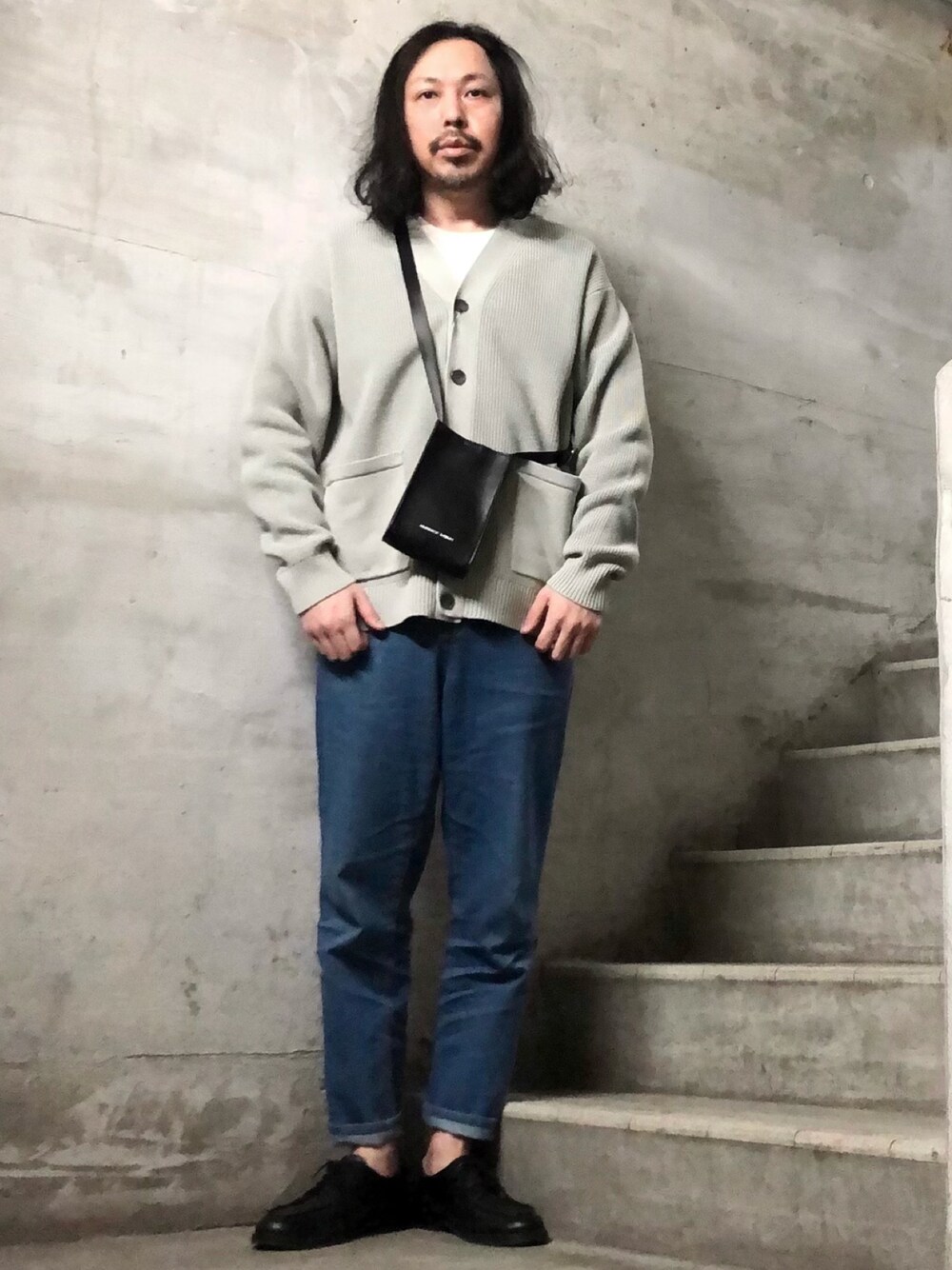 ブラック系のショルダーバッグ、ホワイト系のカーディガン/ボレロ、ホワイト系のTシャツ/カットソーを着用したメンズの冬コーディネートの1枚目の写真