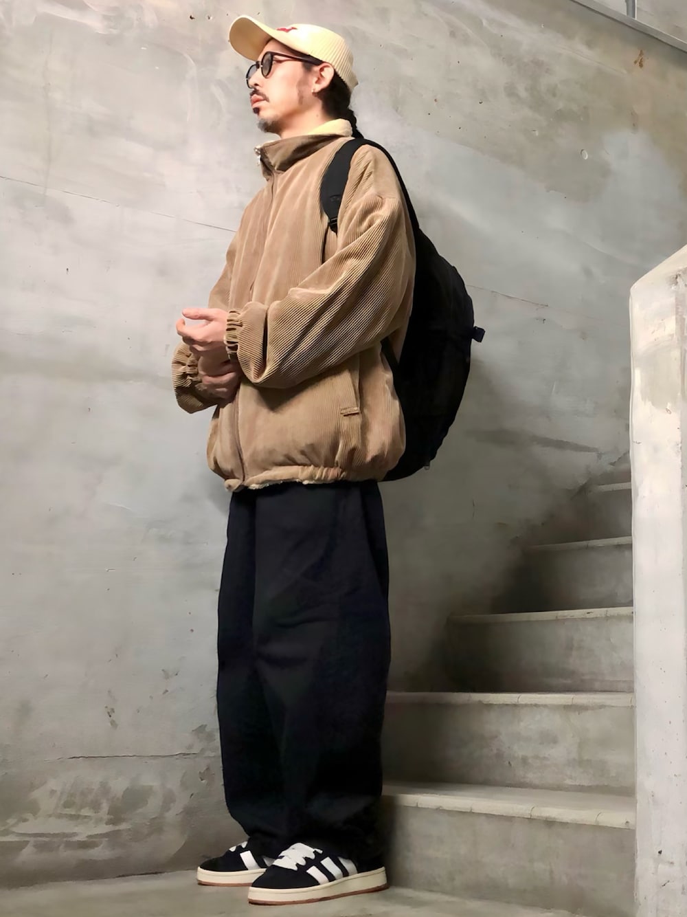 ブラック系のデニムパンツ、ブラック系のスニーカー、ブラック系のバックパック/リュックを着用したメンズの秋コーディネートの1枚目の写真