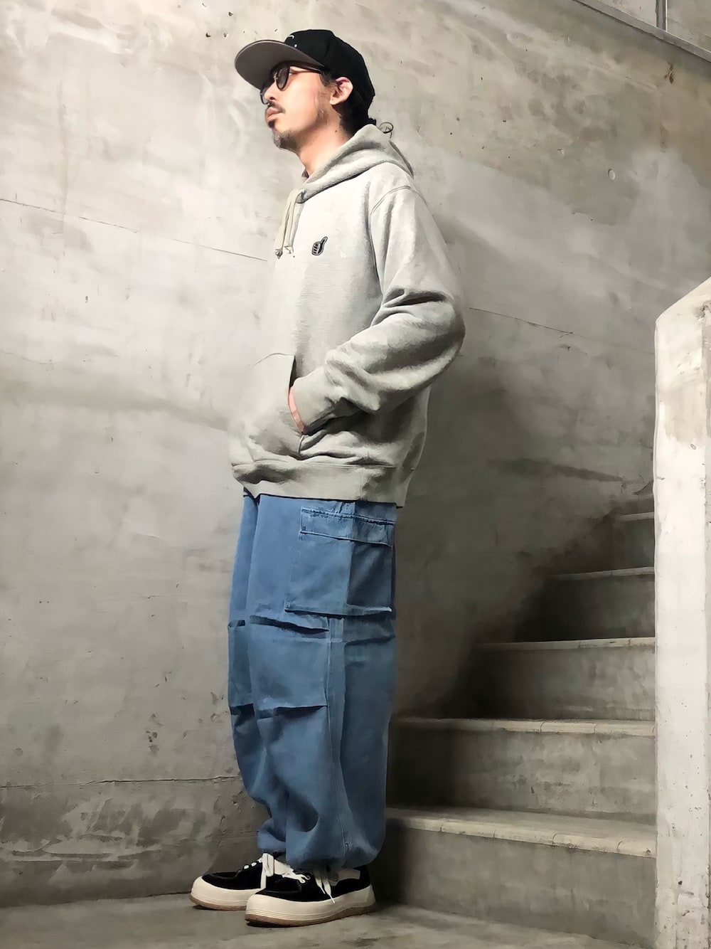 ブルー系のデニムパンツ、グレー系のパーカー、ブラック系のキャップを着用したメンズの冬コーディネートの1枚目の写真