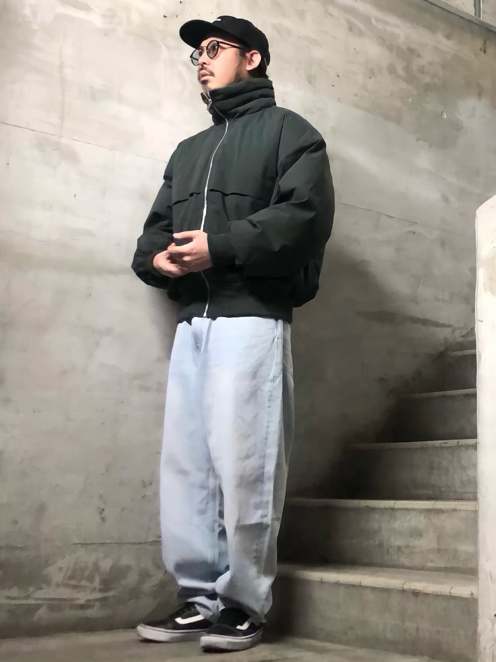 ブルー系のデニムパンツ、グリーン系のブルゾン、ブラック系のスニーカーを着用したメンズの秋コーディネートの1枚目の写真