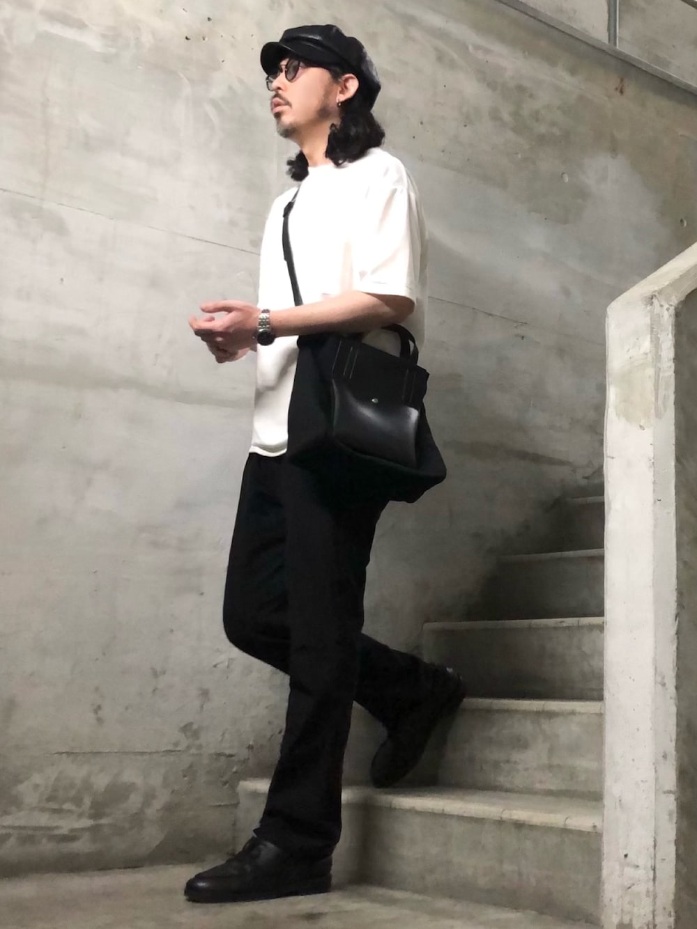 ホワイト系のTシャツ/カットソー、ブラック系のスラックス、ブラック系のショルダーバッグを着用したメンズの春コーディネートの1枚目の写真