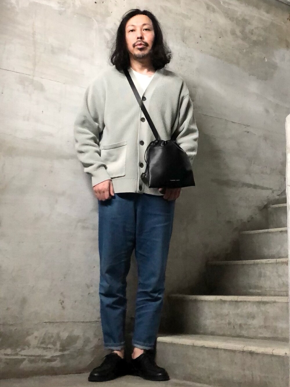 ブラック系のショルダーバッグ、ホワイト系のカーディガン/ボレロ、ホワイト系のTシャツ/カットソーを着用したメンズの冬コーディネートの1枚目の写真