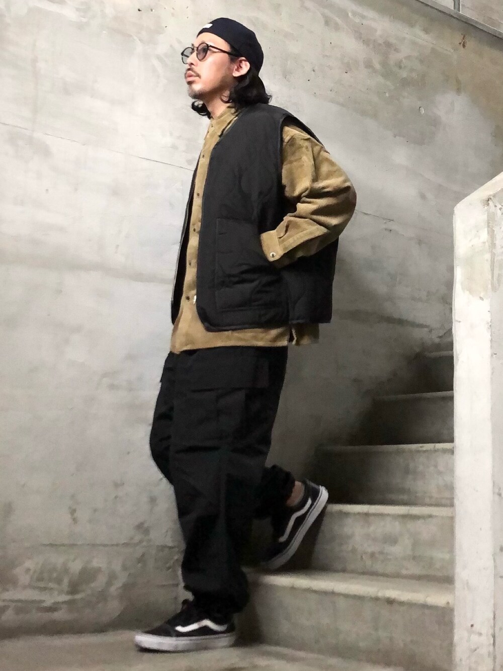 ベージュ系のシャツ/ブラウス、ブラック系のベスト、ブラック系のカーゴパンツを着用したメンズの秋コーディネートの1枚目の写真