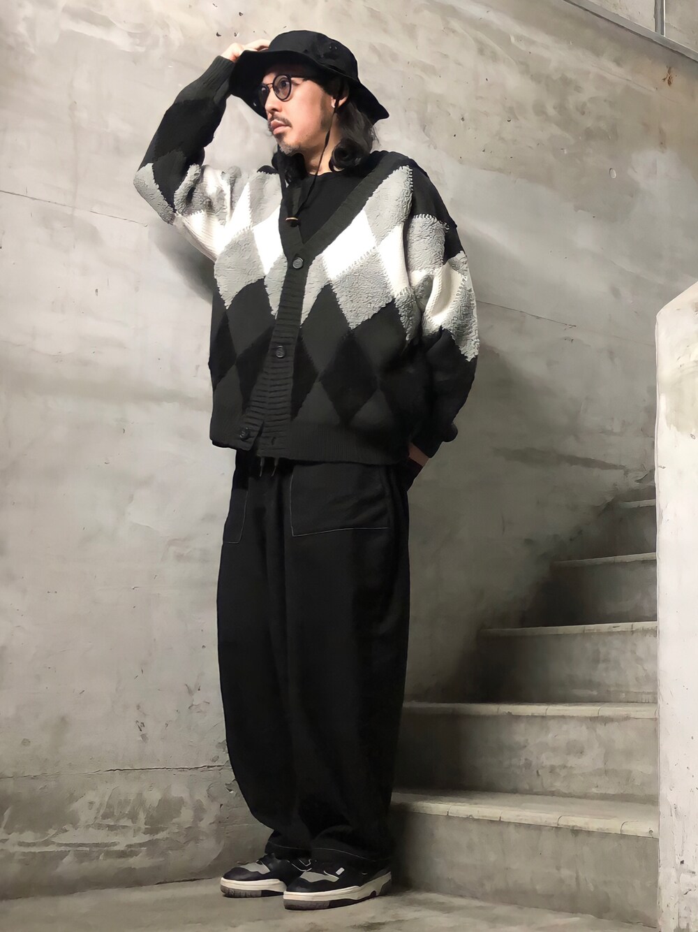 ブラック系のカーディガン/ボレロ、ブラック系のスニーカー、ブラック系のハットを着用したメンズの秋コーディネートの1枚目の写真