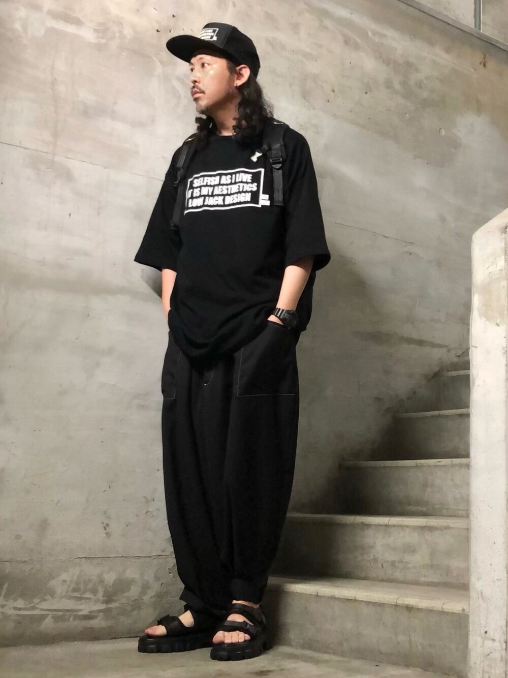 ブラック系のサンダル、ブラック系のTシャツ/カットソー、ブラック系のキャップを着用したメンズの夏コーディネートの1枚目の写真