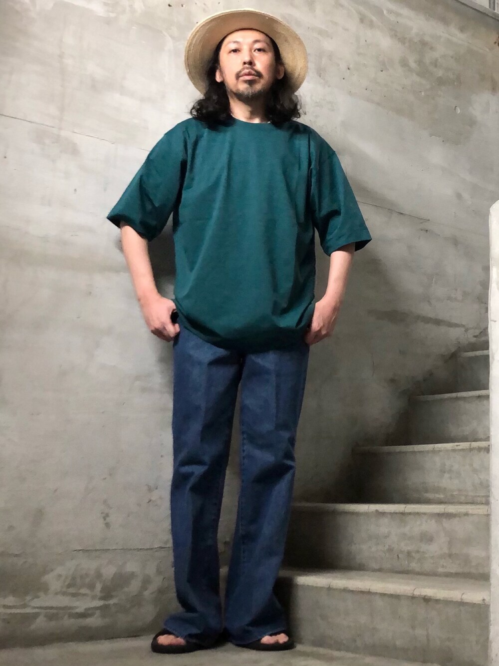 ブルー系のデニムパンツ、グリーン系のTシャツ/カットソー、ホワイト系のハットを着用したメンズの春コーディネートの1枚目の写真