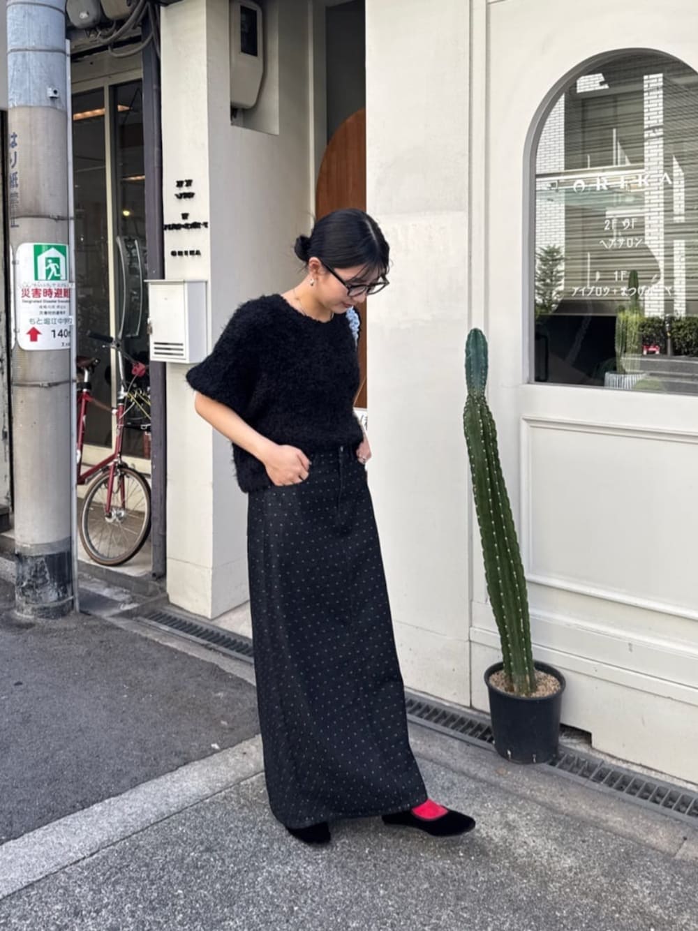 ブラック系のバレエシューズ、ブラック系のデニムスカート、ブラック系のニット/セーターを着用したレディースの秋コーディネートの1枚目の写真