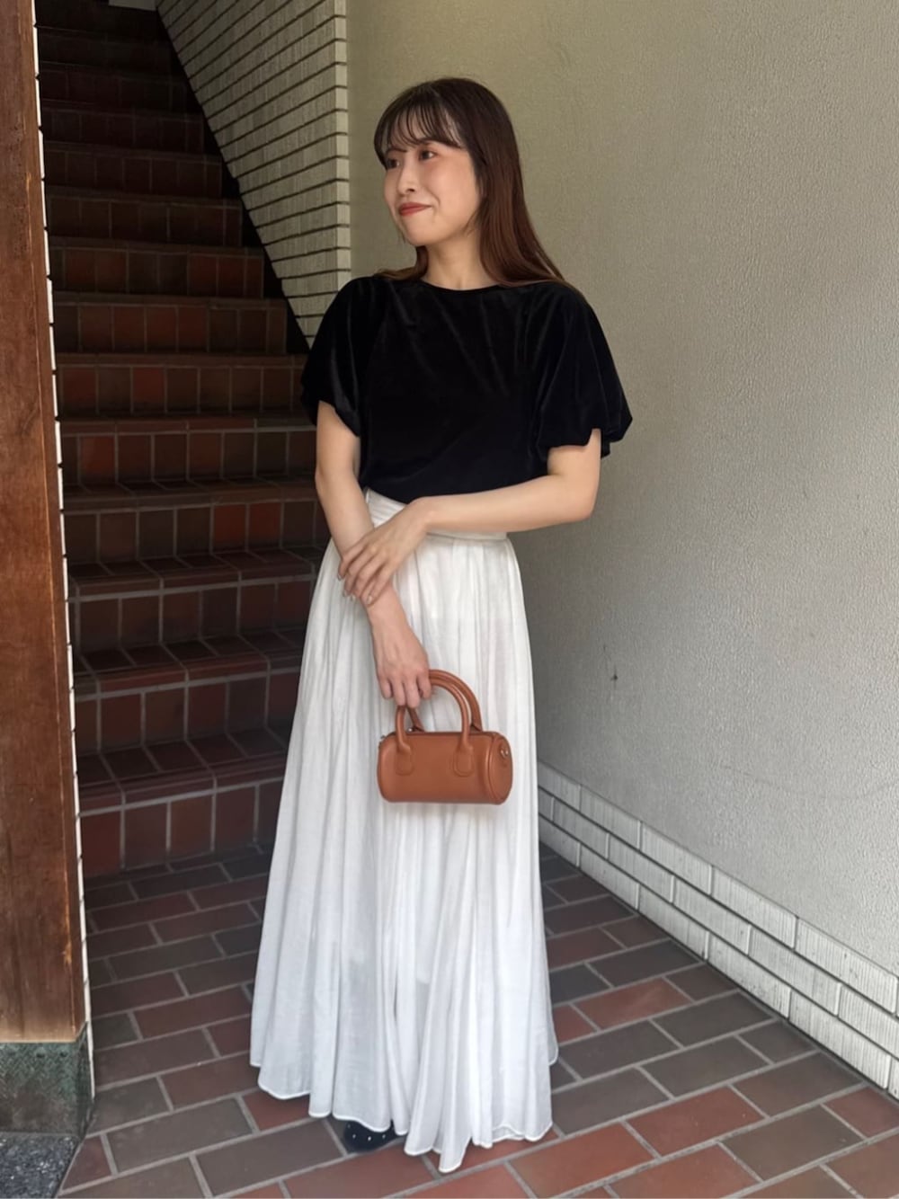 ホワイト系のスカート、ブラック系のTシャツ/カットソー、ブラック系のバレエシューズを着用したレディースの秋コーディネートの1枚目の写真