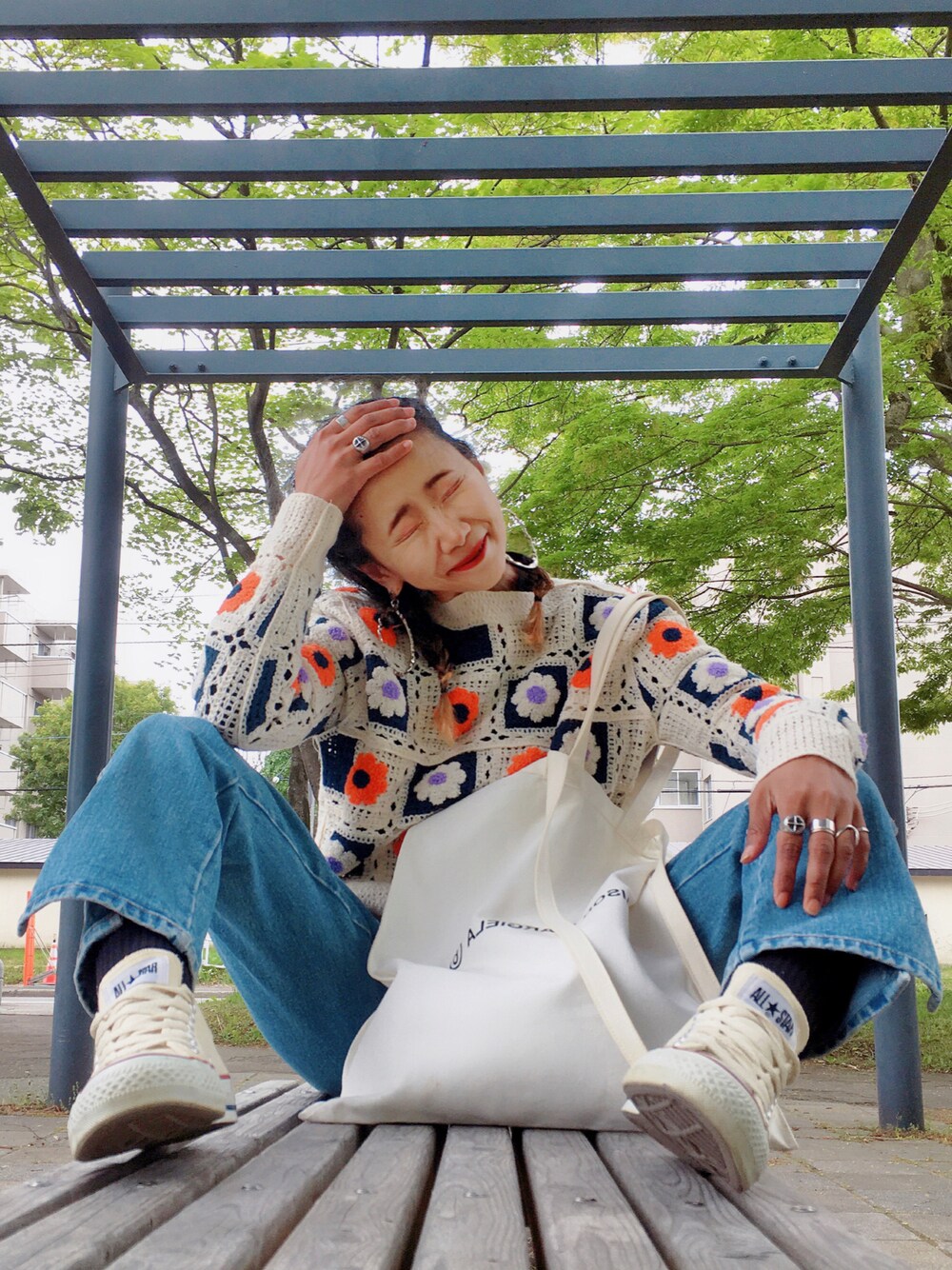 ブルー系のデニムパンツ、ホワイト系のトートバッグ、ホワイト系のスニーカーを着用したレディースの春コーディネートの1枚目の写真