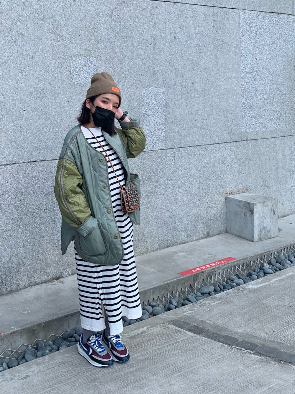 ブラック系のミリタリージャケット、ホワイト系のワンピース、その他のシューズを着用したレディースの冬コーディネートの1枚目の写真