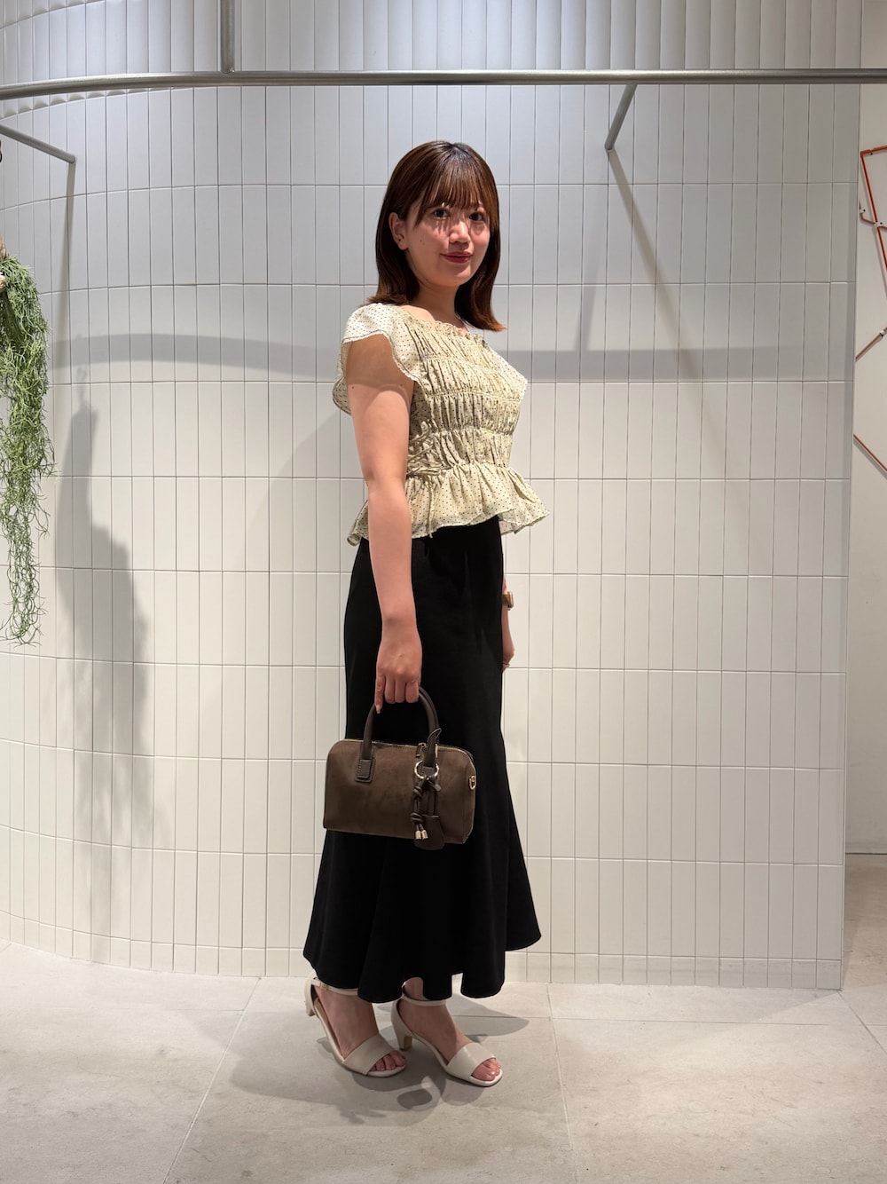 ブラック系のスカート、ベージュ系のシャツ/ブラウス、ブラウン系のボストンバッグを着用したレディースの夏コーディネートの1枚目の写真