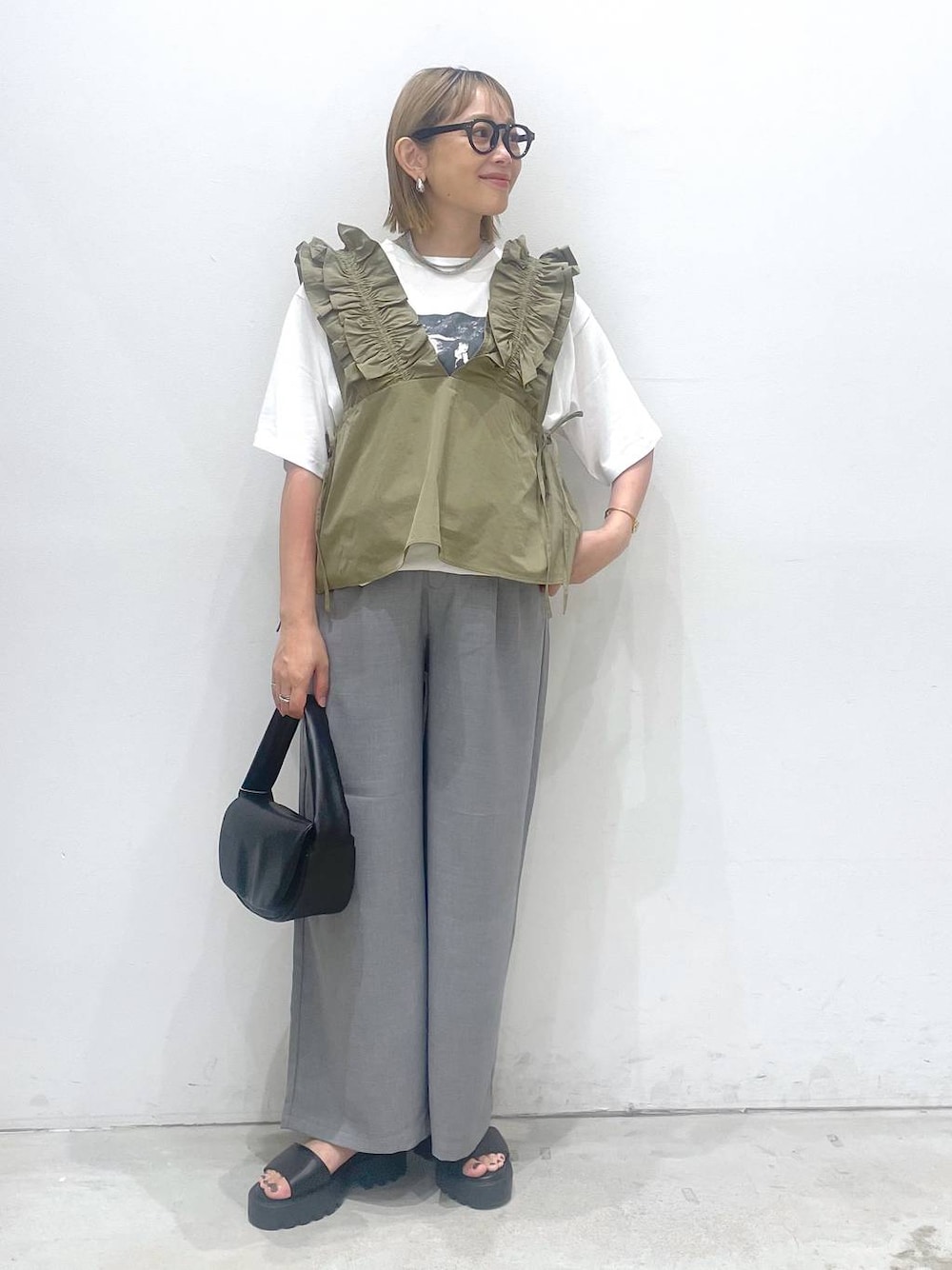 ブラック系のハンドバッグ、ブラウン系のサンダル、グレー系のその他パンツを着用したレディースの夏コーディネートの1枚目の写真