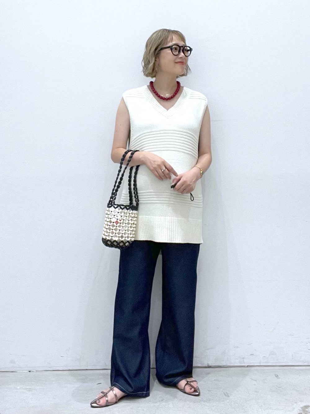 ブルー系のデニムパンツ、その他のサンダル、ホワイト系のハンドバッグを着用したレディースの夏コーディネートの1枚目の写真