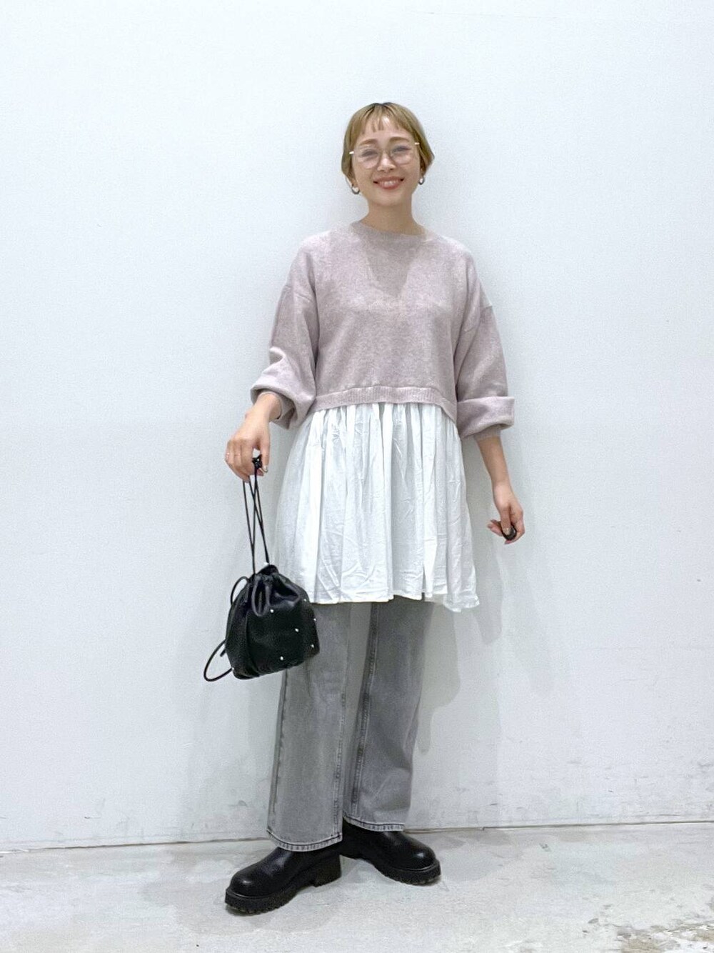 ブラック系のショルダーバッグ、グレー系のデニムパンツ、ブラック系のブーツを着用したレディースの秋コーディネートの1枚目の写真